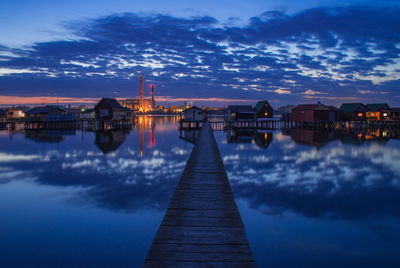 Pier over lake against sky at sunset