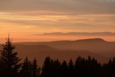 Scenic view of silhouette mountains against orange sky