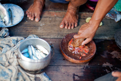 Hands preparing red chili paste in mortar and pestle