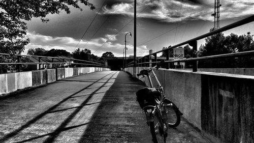 Bicycle parked on bridge against sky