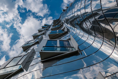 Exterior windows align on reflected metal sheet curvature facade at madiahafen.