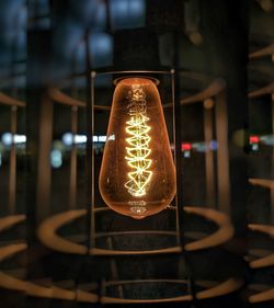 Close-up of illuminated light bulb hanging on ceiling