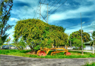 Electricity pylon on field against cloudy sky