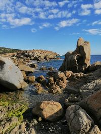 Rocks on shore by sea against sky