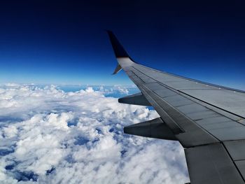 Airplane flying over clouds against blue sky