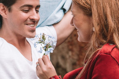 Close-up of smiling woman holding flowers by man