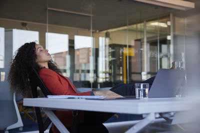 Businesswoman resting with eyes closed at desk in office