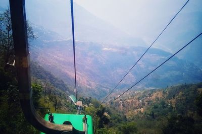 Overhead cable car over mountains against sky