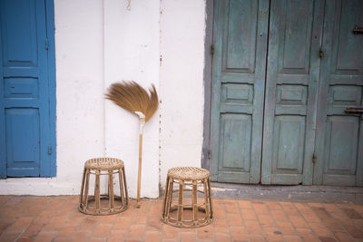Stools and broom by closed doors outside house