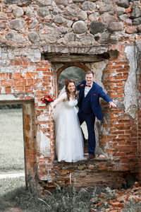 Bride and groom standing at abandoned wall