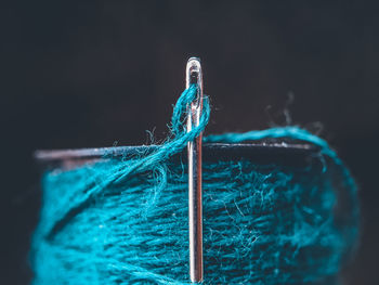 Close-up of a needel and yarn reel against black background