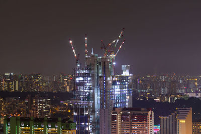 Illuminated buildings in city against sky at night