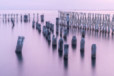 Panoramic view of wooden posts in sea against sky