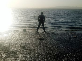 Silhouette man standing on beach against sky during sunset