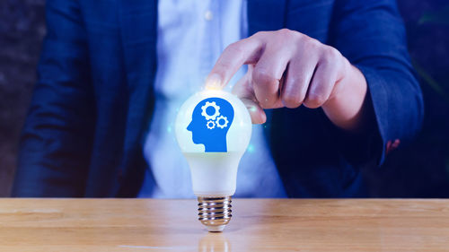 Midsection of man holding light bulb