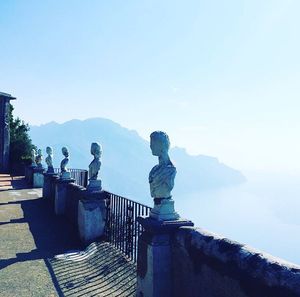 View of a woman sitting against clear blue sky