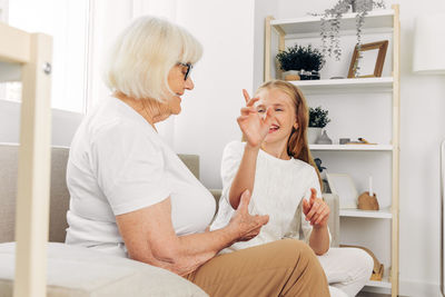 Side view of mother and daughter sitting on sofa at home