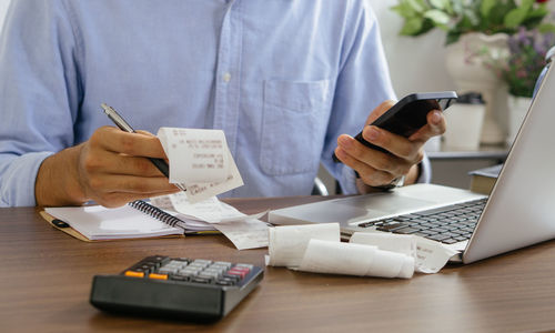 The man holding paper bills using calculator app. calculation financial.