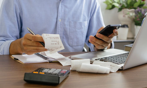 Midsection of man using laptop on table