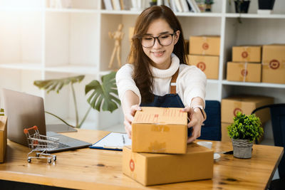 Portrait of young woman using laptop while sitting on table