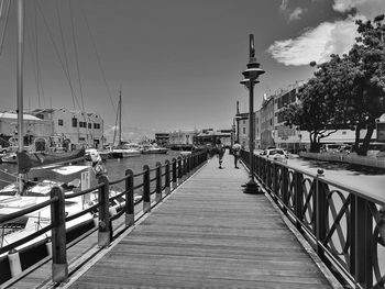 Footbridge over canal in city against sky