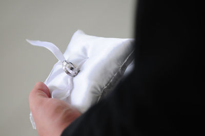 High angle view of man holding wedding rings on small cushion 