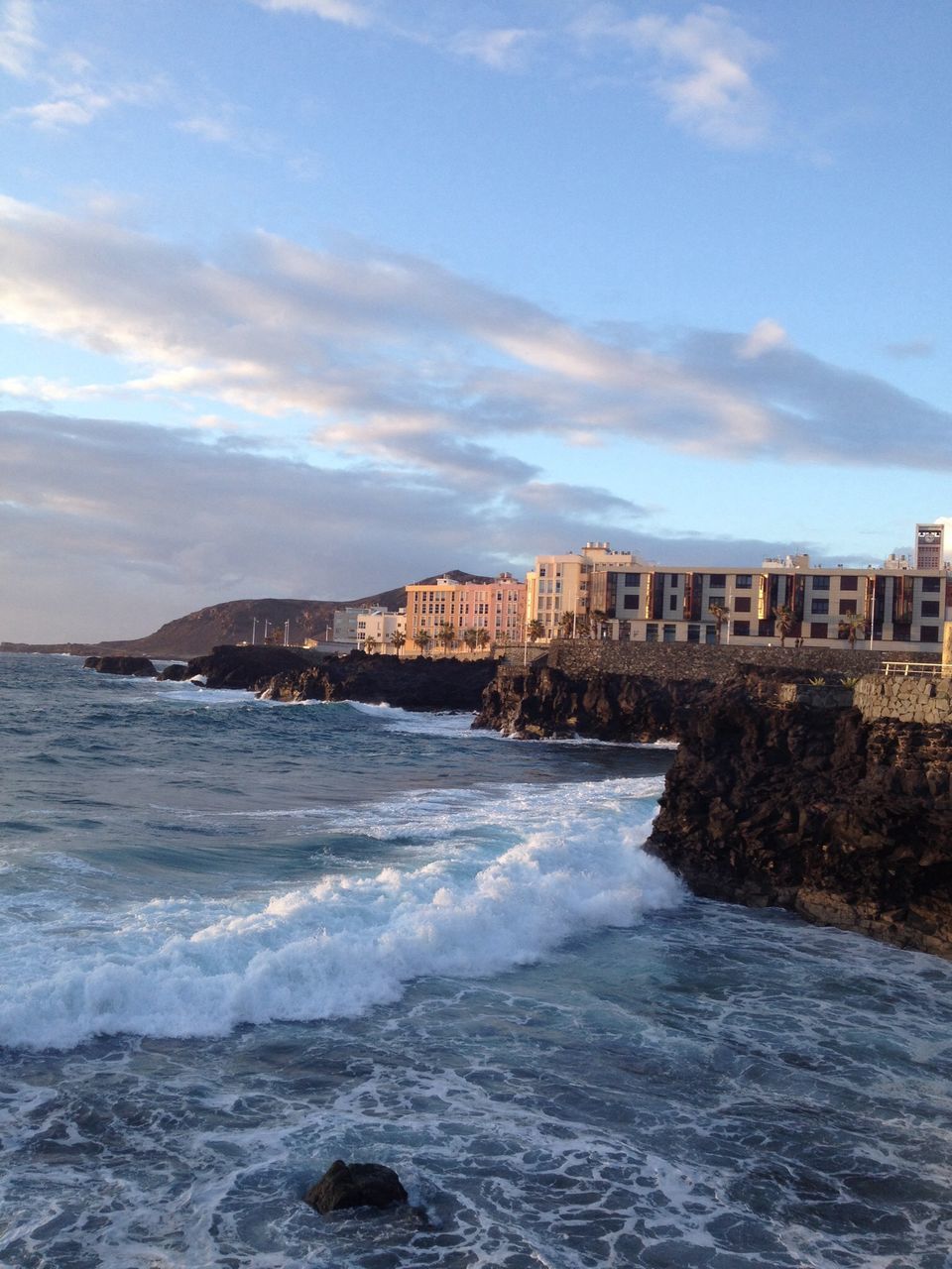 water, architecture, sea, built structure, building exterior, sky, surf, wave, waterfront, city, cloud - sky, motion, nature, splashing, horizon over water, beach, coastline, scenics, cloud, shore