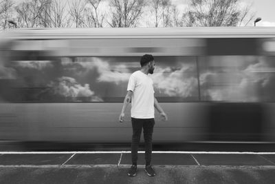 Man standing by train moving on railroad station