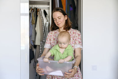 Mother carrying baby boy in plastic container