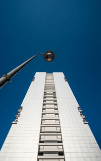 Low angle view of building and street light against clear blue sky