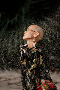 Portrait of young woman standing against waterfall