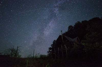 Low angle view of log cabin with stars in sky at night
