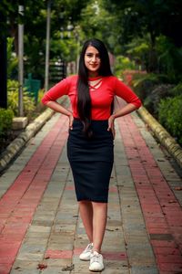 Portrait of young woman standing on footpath