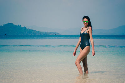 Woman wearing swimsuit standing in sea at beach