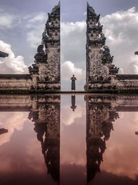 Man standing at entrance of temple with refection against sky