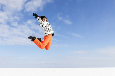 Low angle view of woman jumping against sky