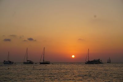 Sailboats in sea against sky during sunset