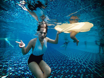 Portrait of woman swimming underwater in pool