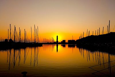Silhouette sailboats in lake against orange sky