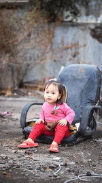 Portrait of cute girl sitting in pink dress look at the camera