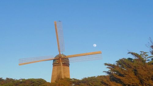 Low angle view of windmill against clear blue sky