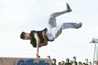 Rear view of a woman jumping against the sky