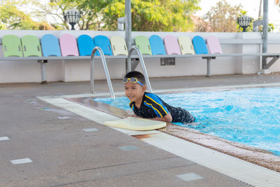 Portrait of boy sitting on swimming pool