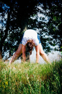 Young woman exercising on grassy field