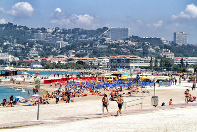 People enjoying at beach against cityscape