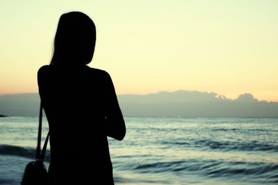 Rear view of silhouette woman standing at beach