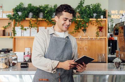 Portrait of young man using digital tablet while standing in cafe