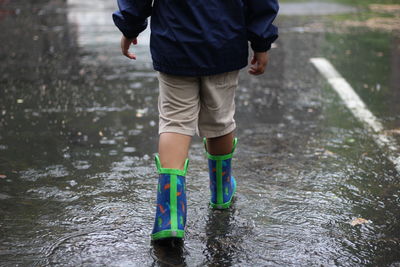 Low section of boy walking in puddle