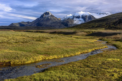 Scenic view of stream by mountains against sky