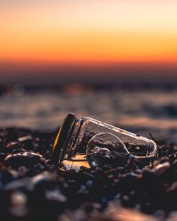 Close-up of light bulb in jar at beach during sunset